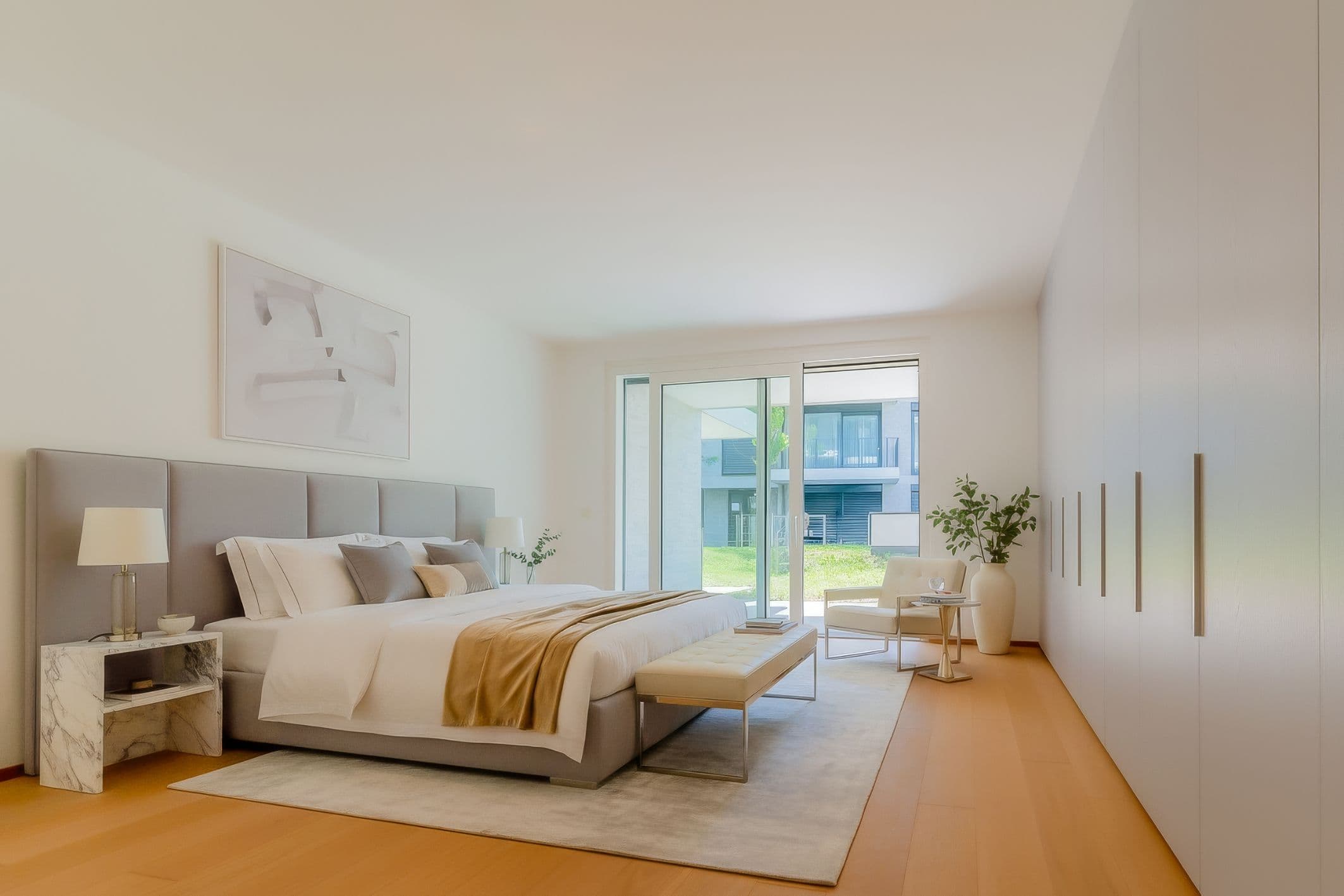 Helles Schlafzimmer einer Park Suites Wohnung mit bodentiefen Fenstern und Blick ins Grüne